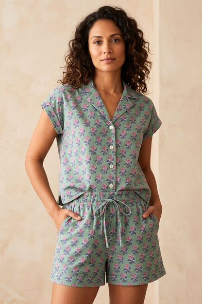 Woman wearing a floral pajama set against a beige wall.