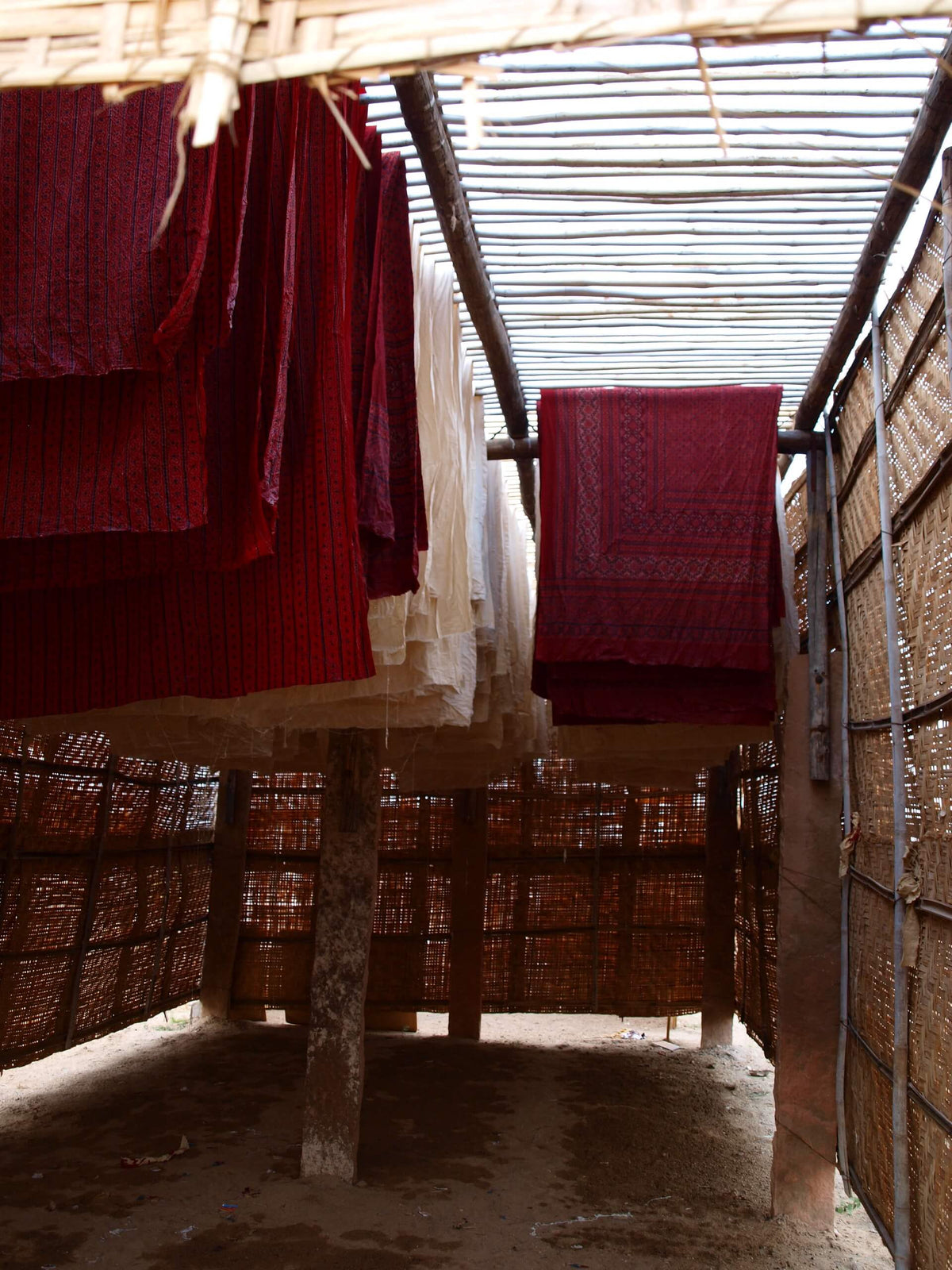 Lengths of printed cotton drying under a bamboo-thatch structure