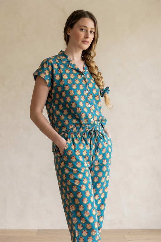 Woman wearing a teal and orange patterned jumpsuit against a plain background