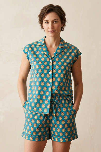 Woman wearing a teal and gold pineapple patterned pajama set against a beige background