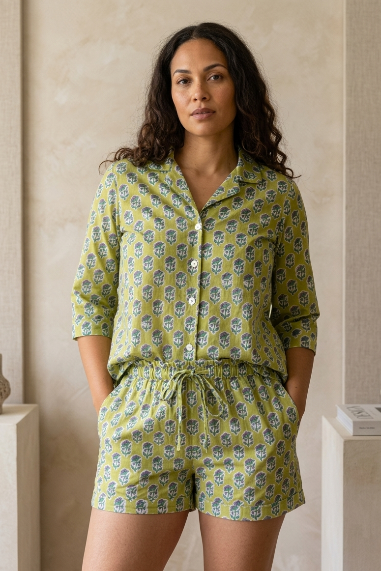 Woman wearing a green patterned pajama set standing against a neutral wall.