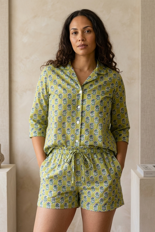 Woman wearing a green patterned pajama set standing against a neutral wall.