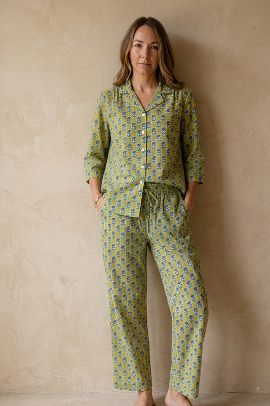 Woman wearing a green patterned pajama set against a beige wall
