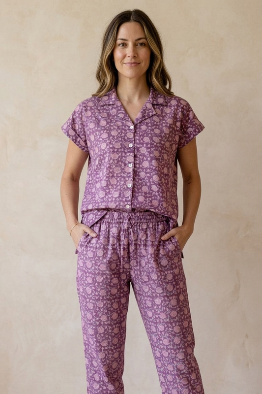 Woman wearing a purple floral pajama set against a beige background