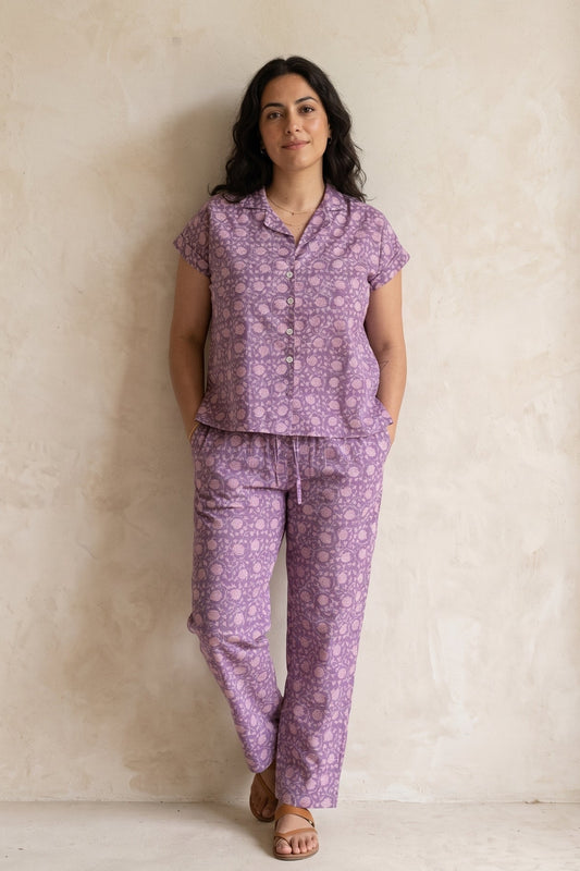 Women standing against a wall wearing matching purple Pajama set