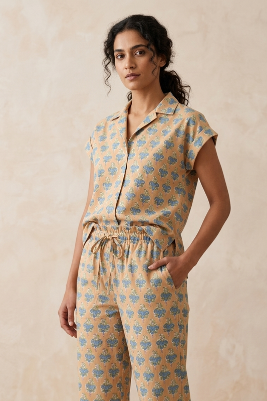 Woman wearing a matching sleeveless top and pants with a floral pattern on a beige background