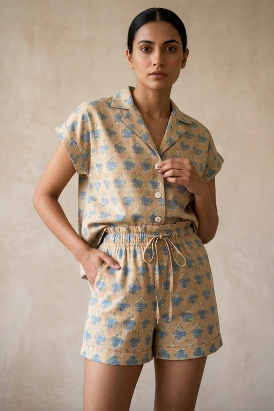 Woman wearing a patterned shirt and shorts set against a beige background