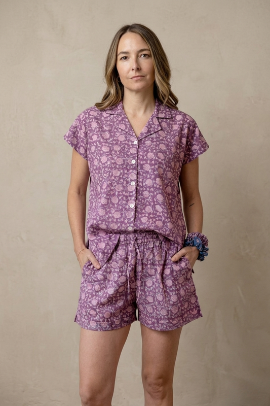 Woman wearing a purple patterned outfit against a beige background