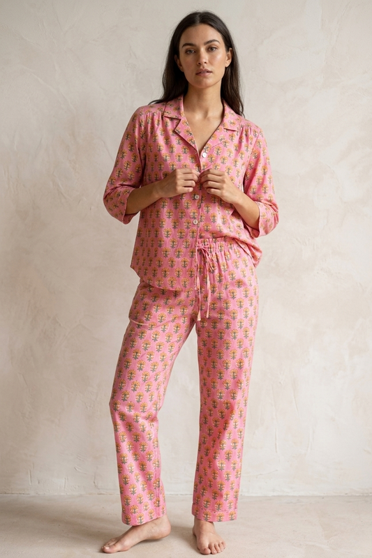 Woman wearing a pink patterned pajama set against a beige background