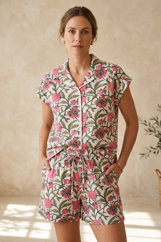 Woman wearing a floral romper against a beige wall.